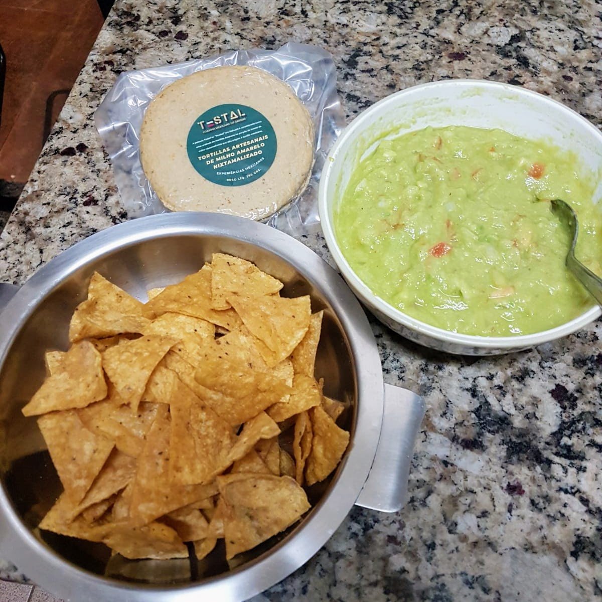 Nachos feitos com tortilha de milho cortada, servidos com guacamole fresco